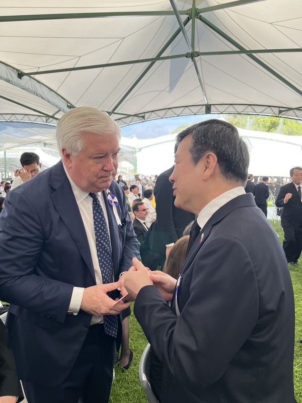 駐日代表の李逸洋氏（右）は台湾を代表して出席し、開会前に会場内でアメリカの駐日大使ジョージ・グラス氏（左）と握手を交わし、挨拶をした（写真\中央社）