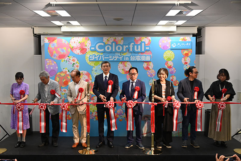 出席者によるテープカットの様子（駐日代表処の周學佑公使（左4）、日本台湾交流協会の谷崎泰明理事長（左3）、日本漫画家協会の里中満智子理事長（右3）、手塚プロダクションの松谷孝征社長（左2）、文化部台湾文化センター（駐日）の曾鈐龍主任（右4）、漫画家の阮光民氏（右2）、左萱氏（左1）、重花氏（右1））