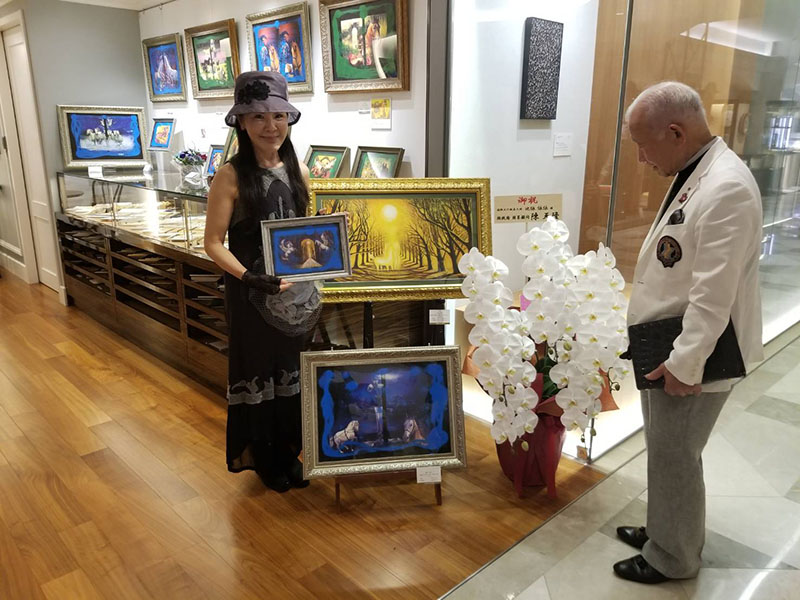 作品を鑑賞する来場者と画家池依依依本人(左)