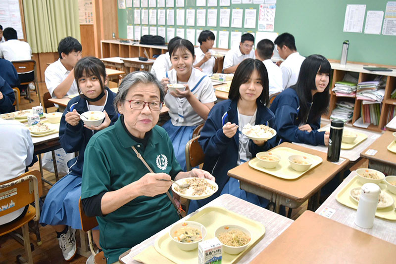 琉球華僑總會宮古支部長羽地芳子(左，綠衣)與學生共享台灣料理營養午餐