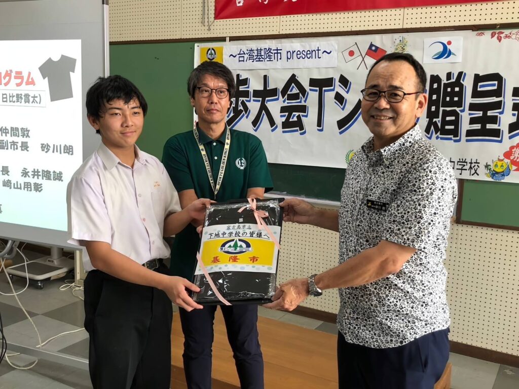 T恤贈呈儀式由宮古島市副市長砂川朗（右）代表接領並移交給校方